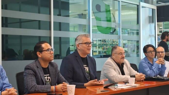 20250926_083423 Empresarios y líderes en una reunión formal en un espacio moderno con ventanales, participando en una discusión importante para el crecimiento económico y desarrollo empresarial en Chihuahua.