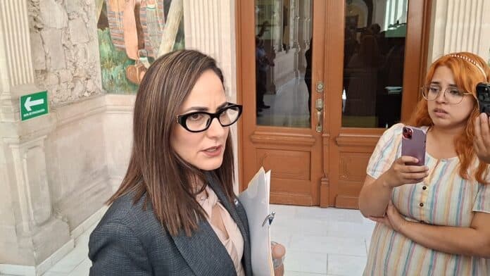 Abogada en entrevista, haciendo declaraciones en un edificio histórico en Chihuahua, México, en un contexto legal y de política, enfocada en temas de justicia y derechos.