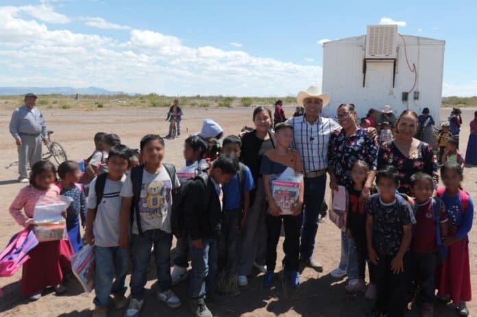 Camión móvil con niños y docentes en una comunidad rural de Chihuahua, con cielo despejado y paisaje semiárido, promoviendo educación y bienestar en zonas rurales de Chihuahua.