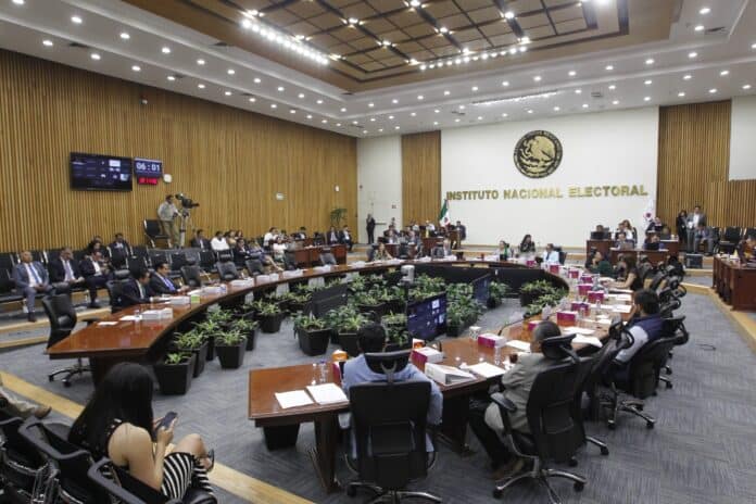 Decoración moderna y formal en el Palacio Legislativo del INE en Chihuahua, con integrantes de la asamblea legislativa participando en una sesión importante, mostrando un ambiente institucional y de trabajo administrativo.