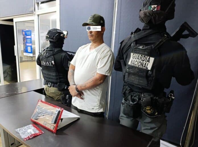 Pensionado durante su arresto por la policía en presencia de elementos de la Guardia Nacional y policías SWAT en un entorno de oficina.