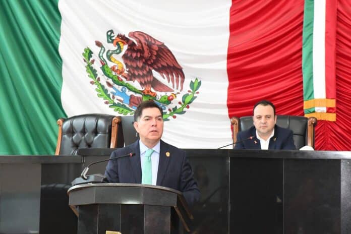 IMG-20250925-WA0072 Acción de una reunión oficial en el Congreso de Chihuahua con la bandera de México de fondo, resaltando temas políticos y gubernamentales relevantes en la entidad.