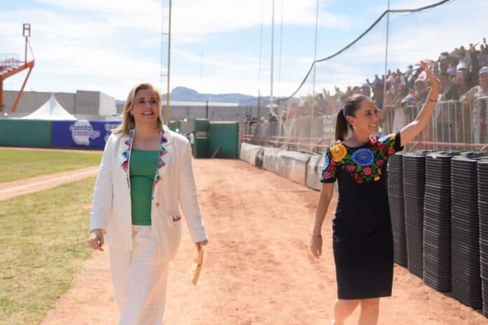 IMG-20250926-WA0046 Calle de béisbol en Chihuahua, evento deportivo con público animado y mujeres destacadas, en un entorno al aire libre con cielo despejado y montañas al fondo.