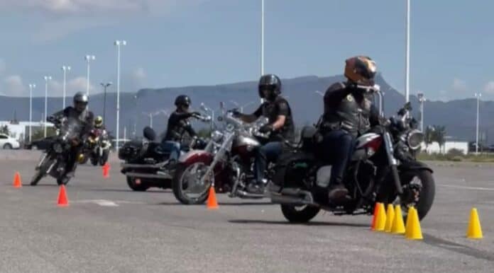 Motoclubs en Chihuahua realizando entrenamiento de manejo y seguridad en motocicleta en un parqueadero. Participantes con cascos y equipo adecuado, siguiendo prácticas de conducción segura.