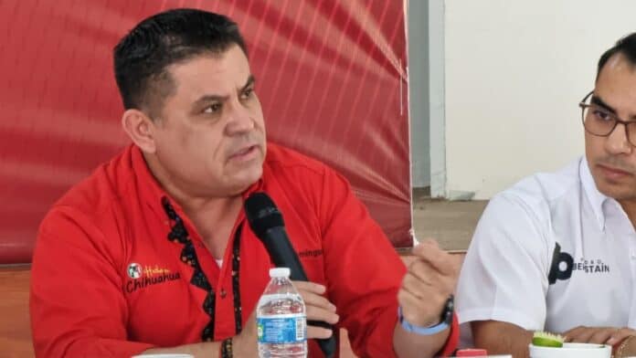 IMG-20250929-WA0035 Hombre en una conferencia política en Chihuahua, usando camisa roja y sosteniendo micrófono, promoviendo el Partido Revolucionario Institucional (PRI), en evento con enfoque en política local.