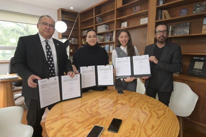 IMG-20250929-WA0057 Firma de acuerdo institucional en oficina moderna con profesión./ Gente sonriente y formal sosteniendo documentos en reunión de negocios.