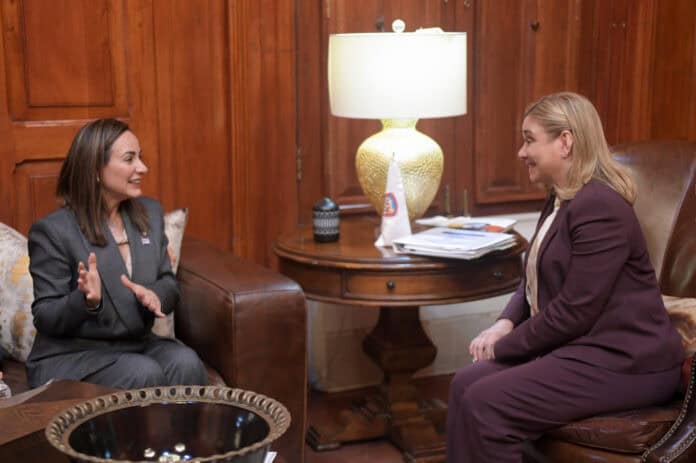 IMG-20250930-WA0086 - Mujeres en una reunión formal, sentadas en una oficina con paredes de madera, hablando y sonriendo, en un ambiente de trabajo profesional, promoción de liderazgo y networking femenino.