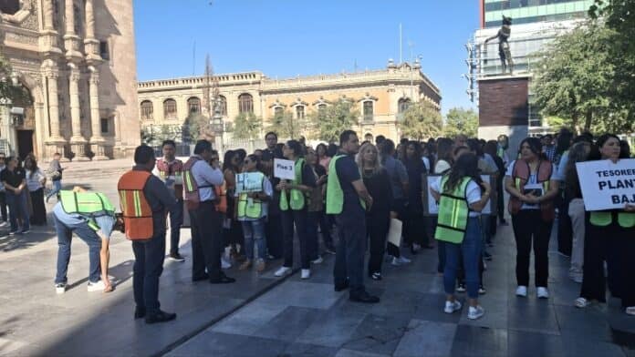 Crítica protestas de empleados en la plaza principal de Chihuahua, con visibilidad de signos y vestimenta de seguridad, en un contexto de movilización laboral.