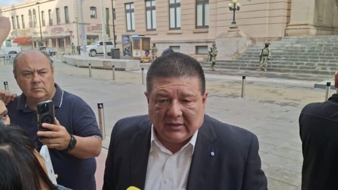 Hombre en traje blanco y negro siendo entrevistado en la calle con fondo de edificios históricos en Chihuahua, México.