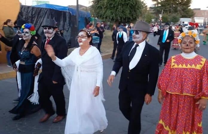 abuelcatri Calabaceado tradicional de Día de Muertos en Chihuahua con personas disfrazadas de calaveras y catrinas bailando en la calle.