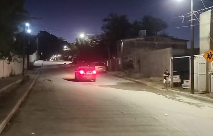 ateindealum Autos en calles urbanas en Chihuahua, imagen nocturna, iluminación pública y tráfico ligero, ambiente de ciudad, personas caminando en las aceras, calles con pavimento, zona residencial tranquila.