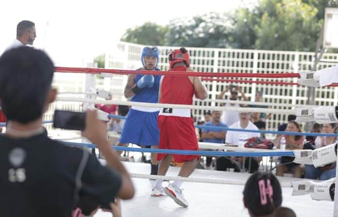 Luchadores de boxeo en un combate amateur en un torneo en Chihuahua, participando en una pelea deportiva con público observando el evento.