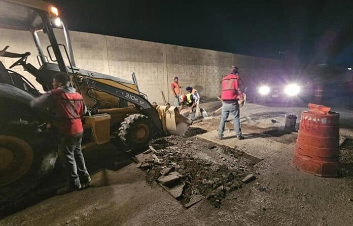 callesobrasjrz Residentes y trabajadores en una obra vial nocturna en Chihuahua, con maquinaria pesada y señalización de seguridad para mejorar las calles de la ciudad.