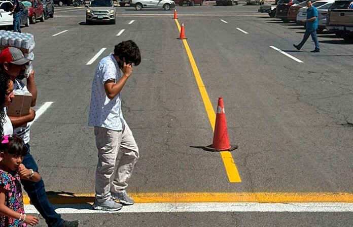 Archivo de tráfico y peatones en una calle de Chihuahua, México, con conos de advertencia y líneas de señalización vial. Imagen representativa del tránsito urbano y seguridad vial en la ciudad.