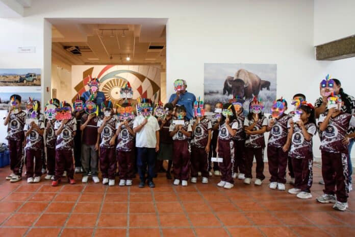 tarike cultura Colaboradores y niños con máscaras tradicionales en una actividad cultural en un museo de Chihuahua, promoviendo la cultura indígena y el arte local en la comunidad.
