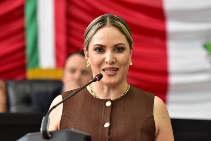 296717be-749e-4521-889a-2bd4b390beb8 Sujeto hablando en un evento formal, con bandera de México de fondo, en un entorno político, resaltando liderazgo y participación ciudadana en Chihuahua.