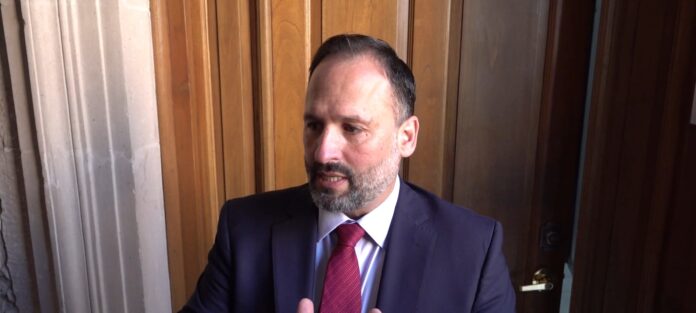 AM Santiago de la Pena, SGG HD(1) Autoridad en entrevista, hombre vestido con traje y corbata en un entorno formal y moderno.