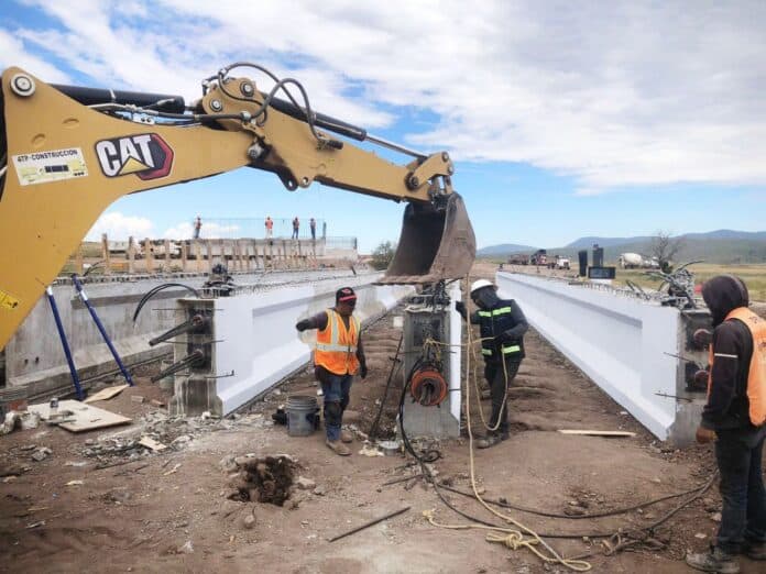 Maquinaria y trabajadores construyendo una infraestructura de puente en un proyecto vial en Chihuahua, enfocándose en obras de ingeniería civil y construcción de puentes en la región.
