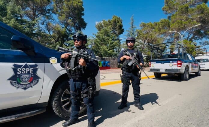 Personal policial en operativo en Chihuahua, México, con vehículos de la SSP, portando armas largas, en una acción de seguridad pública en un día soleado en un lugar con árboles y señalización urbana.