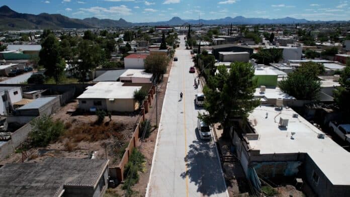 Lavado de calles en Chihuahua, México, con calles pavimentadas, casas residenciales, árboles y montañas en el horizonte.