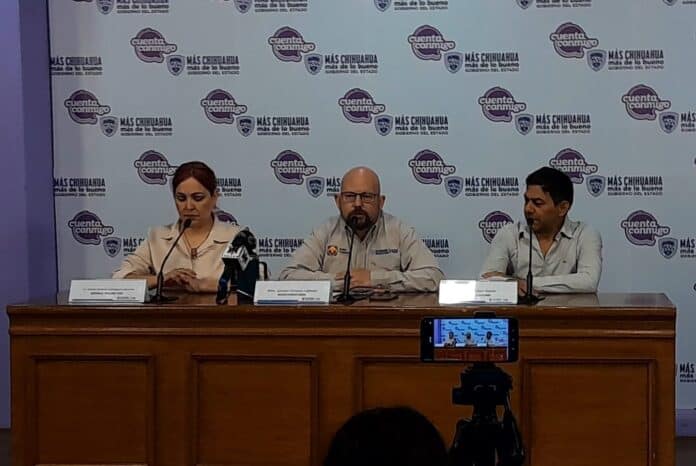 IMG-20251009-WA0019 Union de la prensa en Chihuahua durante conferencia de gobierno estatal; funcionarios en mesa, fondo con logotipo oficial y cámaras captando el evento para noticias.
