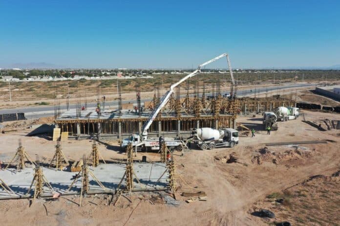 Cimentación en construcción de un edificio en desarrollo en Chihuahua, México, con maquinaria de concreto y estructura en proceso, mostrando avance en obra civil.