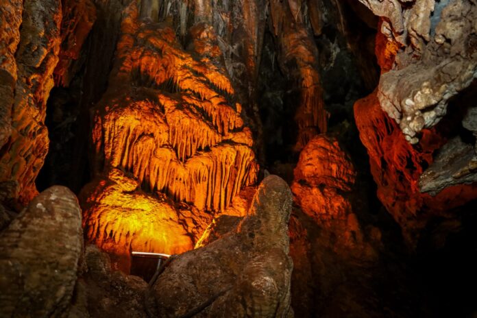 Formaciones de estalactitas y estalagmitas en una cueva de Chihuahua iluminadas con luz cálida, mostrando la belleza natural del interior de la geología regional que atrae a turistas y exploradores.