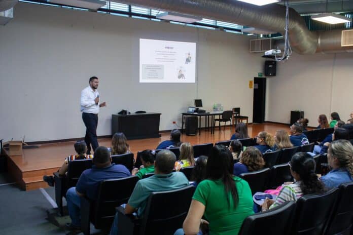 Presentador dando conferencia en auditorio con público atento, en evento de capacitación o seminario en Chihuahua, enfoque en educación y formación profesional.