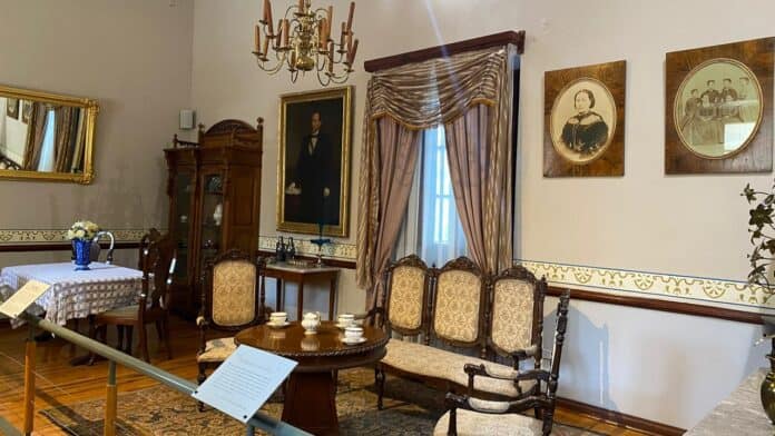 IMG-20251011-WA0073 Elegante sala de museo con mobiliario antiguo, retratos históricos y detalles decorativos clásicos, ideal para apreciar la cultura y la historia de Chihuahua.
