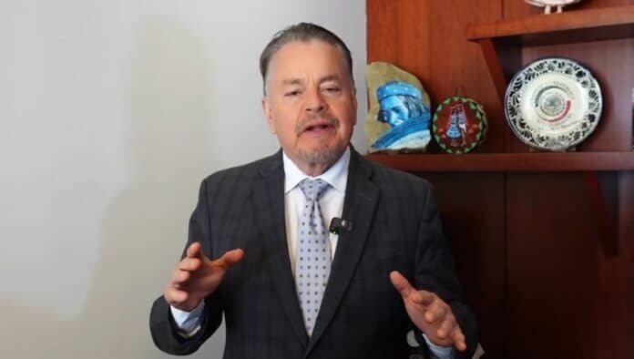 VID-20251010-WA0042 Consejero de negocios en traje oscuro hablando en cámara, fondo con cerámicas tradicionales mexicanas, promoviendo contenido educativo y cultura de Chihuahua.