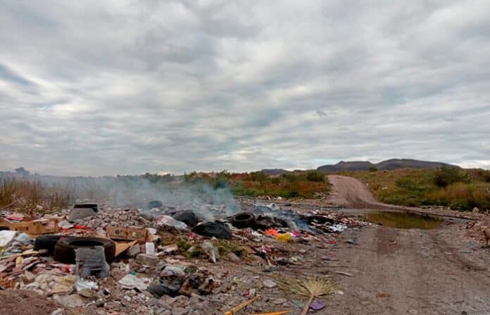 Basura y desechos en un área rural con contaminación, residuos domésticos y neumáticos, en un entorno natural con cielo nublado, en una zona de Chihuahua, México.