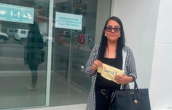 Estudiante con señal de apoyo en universidad en Chihuahua, México, lista para sus estudios y futuras metas académicas, promoviendo educación y desarrollo profesional en la comunidad.