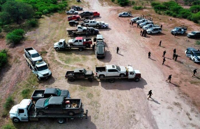operadespli Camiones y autos en un operativo de seguridad en una zona rural de Chihuahua, con varias personas presentes, posible intervención para el control de incidentes o actividades ilícitas.
