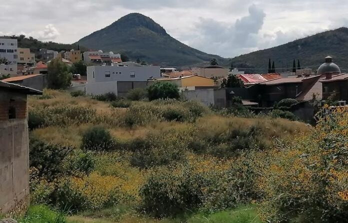 Prado y vista del volcán en Chihuahua, México, con casas y áreas verdes en primer plano, ideal para inversiones inmobiliarias en zonas urbanas y rurales de la región.