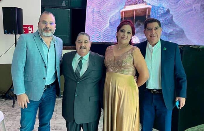 verdecompro Personas en evento formal en Chihuahua, México, vestidas elegantemente, participando en una reunión o celebración profesional, con entorno corporativo y tecnología moderna.